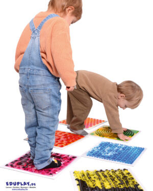Sensorikmatten - Sinne erleben und fördern Das 6-teilige Sensorikmatten-Set mit verschiedenen Oberflächenstrukturen bietet Kindern spannende sensorische Erlebnisse. Jede Matte hat eine einzigartige Oberfläche: ein Labyrinth, eine Blätterstruktur, sechseckige Pyramiden und runde Noppen, die mit Händen und Füßen erkundet werden können. Beim Fühlen und Balancieren werden taktile Reize gesetzt, die Feinmotorik, Gleichgewicht und Körperkoordination spielerisch fördern. Die bunten Farben und Strukturen regen die Fantasie an. Material: PVC, PE, Wasser mit farbiger Kosmetikflüssigkeit Maße: 30 x 30 x 1,2 cm